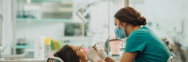 Female dentist examining young woman's teeth.