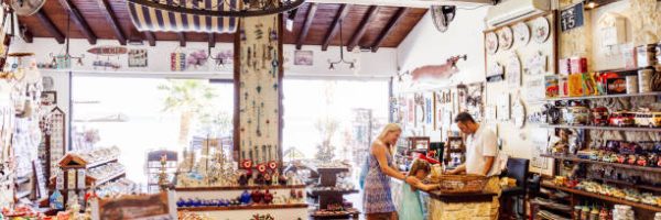 Mother and daughter are buying souvenirs in the Greek gift shop. Real people, authentic scene.