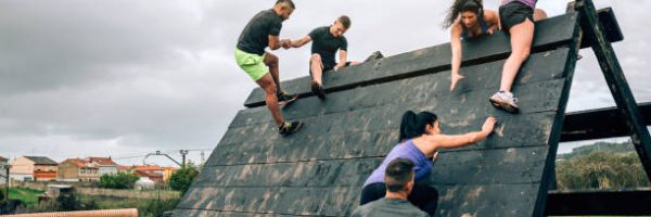 Group of participants in an obstacle course climbing a pyramid obstacle