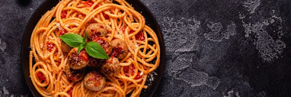 Spaghetti with meatballs and tomato sauce on a stone background, top view