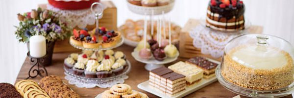 Brown wooden table with various cookies, tarts, cakes, cupcakes and cakepops. Studio shot.