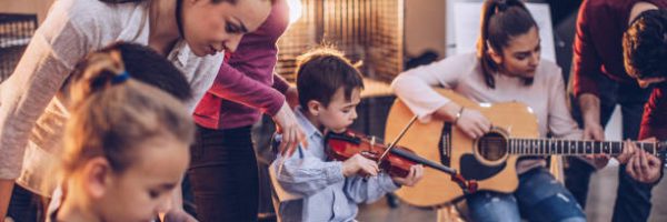 Group of kids teaching to play instruments in music school